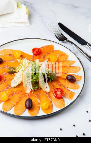 In Scheiben geschnittene rote Fischscheiben mit Kräutern, Kirschtomaten und Weißbrotcroutons Stockfoto