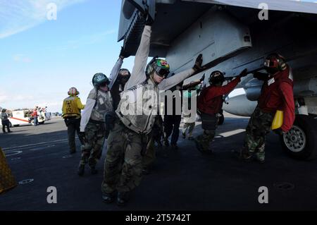 Das Personal des US Navy-Flugdecks schiebt eine F18C-Hornet zurück, die the.jpg zugewiesen wurde Stockfoto