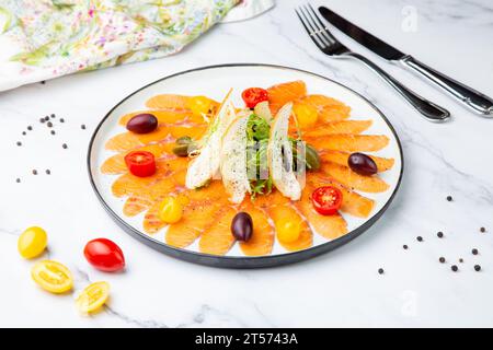 In Scheiben geschnittene rote Fischscheiben mit Kräutern, Kirschtomaten und Weißbrotcroutons Stockfoto