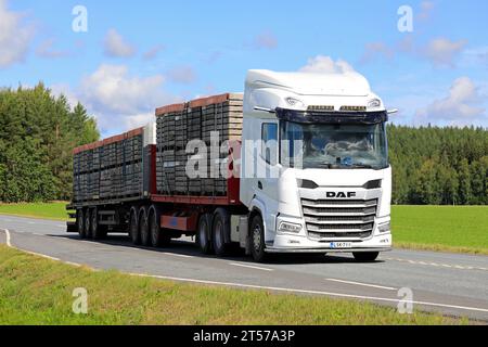 Der weiße neue DAF XF-Lkw transportiert an einem Sommertag eine Ladung Gurkenboxen aus Holz auf einem Pritschenwagen entlang der Straße. Jokioinen, Finnland. Juli 2023. Stockfoto