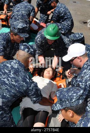 Die Träger der US Navy und Mitglieder des Medical Training Teams bereiten sich darauf vor, die Opfer während einer simulierten Massenbohrung an Bord des amphibischen Transportdocks USS Denver (LPD 9.jpg) an einen sicheren Ort zu bringen Stockfoto