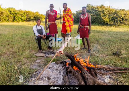 MASAI MARA, KENIA - 20. FEBRUAR 2020: Masai-Männer, die eine Ziegenbein rösten, Kenia Stockfoto
