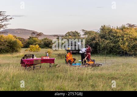 MASAI MARA, KENIA - 20. FEBRUAR 2020: Masai-Männer, die eine Ziegenbein rösten, Kenia Stockfoto