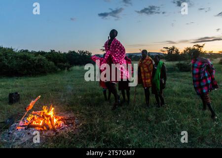 MASAI MARA, KENIA – 20. FEBRUAR 2020: Masai-Männer spielen ihren Springtanz neben einem Lagerfeuer in Kenia Stockfoto