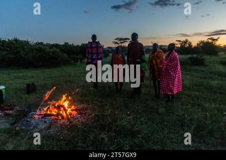 MASAI MARA, KENIA – 20. FEBRUAR 2020: Masai-Männer spielen ihren Springtanz neben einem Lagerfeuer in Kenia Stockfoto