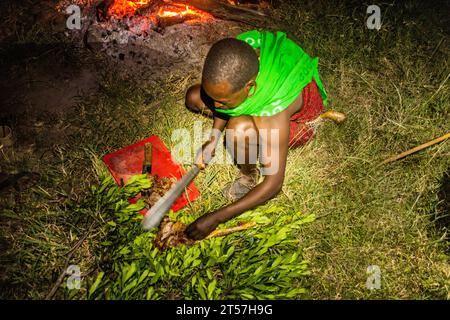 MASAI MARA, KENIA - 20. FEBRUAR 2020: Masai man schneidet ein Ziegenbein, Kenia Stockfoto