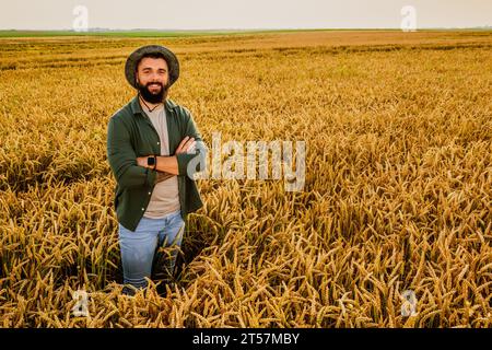 Porträt des Weizenbauers. Er ist zufrieden mit dem guten Fortschritt der Pflanzen. Landwirtschaftliche Tätigkeit. Stockfoto