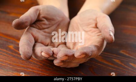 Raue Hände eines weißen erwachsenen männlichen Nahaufnahme vor einem strukturierten Holzhintergrund, dunkel und angeraut durch schwere Handarbeit, leere männliche Handflächen Stockfoto