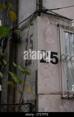 Die Zahl fünfundzwanzig ist dreimal mit einer Schablone auf eine graue Wand an der Ecke des Hauses gemalt, nahe Fenster mit Gittern. Hausnummer 25. Stockfoto