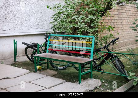 Zwei Fahrräder wurden unbeaufsichtigt auf dem Hof in der Nähe einer bunten Bank gelassen. Sicherheit des Eigentums auf dem Gebiet der GUS-Staaten und der ehemaligen Sowjetunion Stockfoto