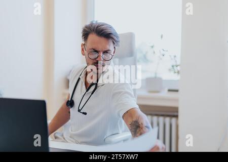 Ein erfahrener Arzt, der medizinische Testergebnisse in einer Indoor-Klinik überprüft, die Betreuung und Behandlung eines Patienten anbietet. Stockfoto