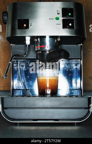 Espresso-Shot-Ausgießen aus der Espressomaschine auf der Arbeitsplatte Stockfoto