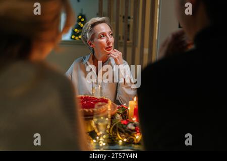 Rückansicht der glücklichen kaukasischen Familie, die zu Hause zu einem Abendessen zu Weihnachten zusammenkommt. Schöne Leute versammelten sich um den Tisch, um Weihnachten zu essen Stockfoto