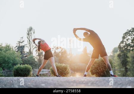Fittes, attraktives Paar, das im Park Sport treibt und sich für Outdoor-Training ausdehnt. Stockfoto