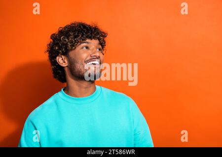 Porträt des netten kreativen Mannes Zahny Lächeln Blick leerer Raum Brainstorming isoliert auf orangefarbenem Hintergrund Stockfoto