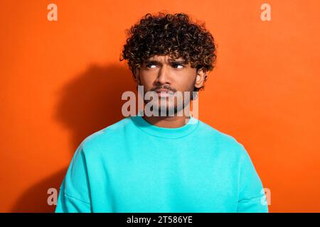 Porträt einer gesinnten nachdenklichen Person, die interessiert im leeren Raum ist, betrachten Sie zögern isoliert auf orangefarbenem Hintergrund Stockfoto