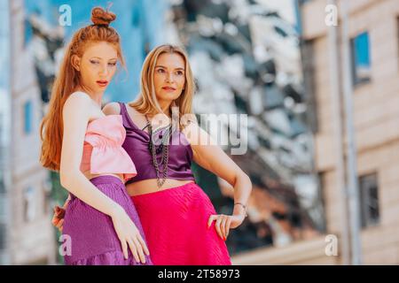 Selbstbewusste und elegante Frauen, die das Leben in der Stadt in stylischen Outfits genießen. Leuchtende Pink- und Lila-Töne. Stockfoto
