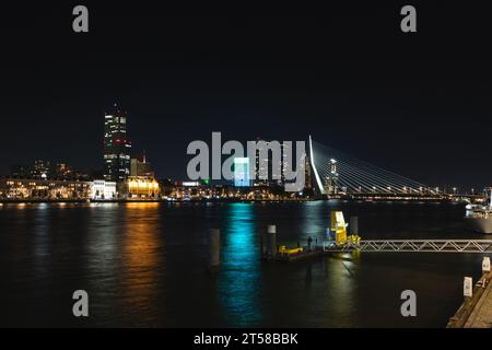 Blick auf den Kanal und die gegenüberliegende beleuchtete Bank mit vielen beleuchteten Wolkenkratzern in der späten Nacht in Rotterdam, Niederlande. Stockfoto