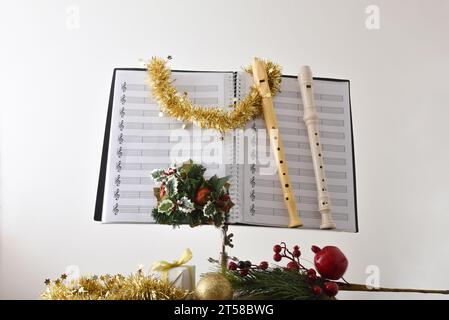 Blockflöten auf Notenständer mit Noten und Weihnachtsdekoration mit religiösem Tempelhintergrund. Vorderansicht. Stockfoto