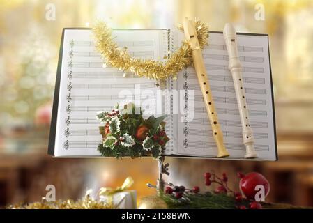 Blockflöten auf Notenständer mit Noten und Weihnachtsdekoration mit religiösem Tempelhintergrund. Vorderansicht. Stockfoto