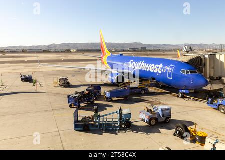 Die Piste des Phoenix Sky Harbor International Airport mit einem Flugzeug der Southwest Airlines, das an einem Gate geladen wird, und Bergen in der Ferne. Stockfoto