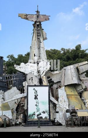 VIETNAM, Hanoi, Militärmuseum, Militärausrüstung und Kriegsschrott aus dem französischen Kolonialkrieg 1946-1954 und dem US-amerikanischen Krieg in Vietnam 1955–1975, Wrack von Grumman F6F Hellcat ein amerikanisches Trägerflugzeug, das von der französischen Kolonialarmee eingesetzt wurde, abgeschossen in der Schlacht in Dien Bien Phu 1954 , berühmtes Foto oder Bild einer vietnamesischen Frau, die einen Flügel eines abgeschossenen US-Flugzeugs zieht Stockfoto