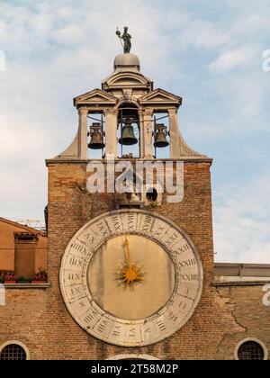 Glockenturm einer Kirche mit drei Glocken, verziert mit einer Uhr mit römischen Ziffern in Venedig, Italien. Stockfoto