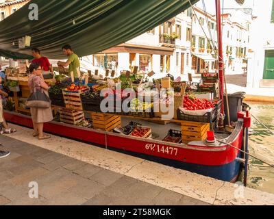 Obst- und Gemüsehändler in Venedig. Seine Besonderheit ist, dass er seine Produkte per Boot auf den Kanälen liefert. Zwei Bootsverkäufer bedienen Kunden auf Stockfoto