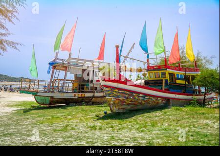 Verlassene Fischerboote in vielen Farben, die an Land am Strand als Restaurants für Touristen verwendet werden Stockfoto