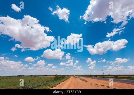 Hellweiße Wolken unter einem hellblauen Himmel über einer Hauptstraße über einer Landstraße in Südafrika Stockfoto