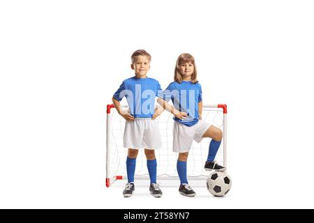 Mädchen und Junge in Sporttrikots posieren mit einem Fußball vor einem Tor isoliert auf weißem Hintergrund Stockfoto