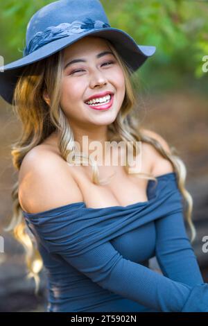 Beauxbatons Hexe bezaubernde junge asiatische Frau mit grauem Langarm-Kleid, Perücke und Hut Stockfoto