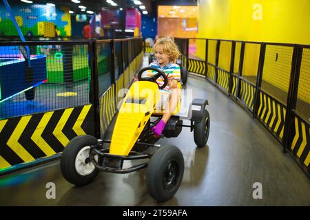 Kinder auf der Kartbahn. Go-Kart-Spaß für Kinder. Junge, der in einem Go-Kart-Auto auf einer Geburtstagsfeier auf dem Spielplatz läuft. Autorennen Abenteuer. Stockfoto