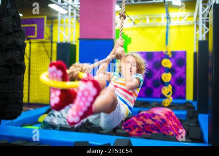 Kind springt im Trampolin-Park. Hüpfspaß auf Kindergeburtstag. Indoor-Spielplatz mit hüpfender Burg. Gesunde Aktivität für Kinder. Stockfoto