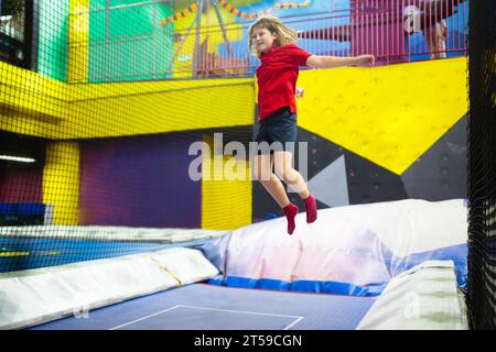 Kind springt im Trampolin-Park. Hüpfspaß auf Kindergeburtstag. Indoor-Spielplatz mit hüpfender Burg. Gesunde Aktivität für Kinder. Stockfoto