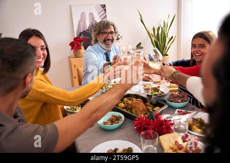 Drei Generationen lächelnder Kaukasier feiern das Leben des Hauses mit Gläsern Weißwein. Stockfoto