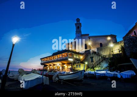 Fantastischer Blick auf den Sonnenuntergang von Boccadasse auf einem Gebäude mit Café oder Restaurant in Genua Vorort. Jetzt Mond im Himmel, viele Boote, die auf Ground Blur versteckt sind Stockfoto