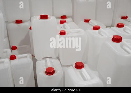 Leere weiße Kunststoffkanister. Für flüssige Nachfüllflaschen und Dosen für den Haushalt in einem Eisenwarenlager. Rote Kunststoffkorkkappen Stockfoto