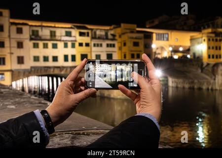 Frauenhände machen ein Foto von Ponte Vecchio auf ihrem Handy. Stockfoto