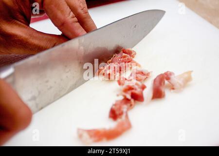 Proscuitto mit einem Messer aufschneiden, um es als Belag zu verwenden Stockfoto