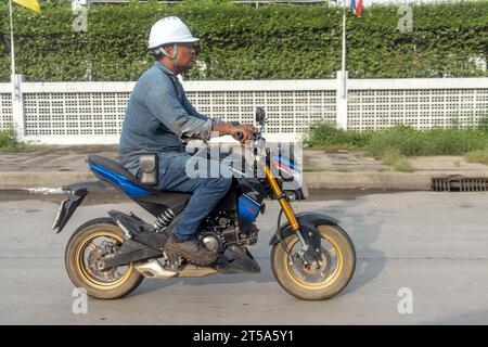 SAMUT PRAKAN, THAILAND, 29. Oktober 2023, Ein Mann mit Arbeitshelm fährt Motorrad Stockfoto