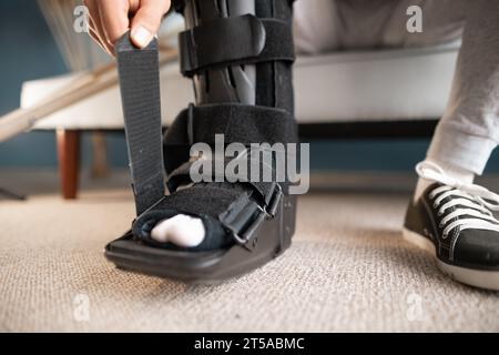 Mann mit Knöchelorthese am Bein, der auf dem Sofa sitzt Stockfoto