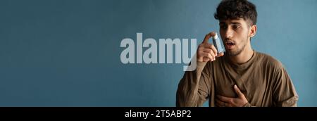 Asthmatiker mit einem Asthmainhalator bei Asthmaanfällen auf blauem Hintergrund. Kopierbereich. Stockfoto