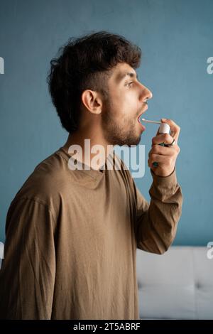 Arabischer Mann, der Medizin im Mund sprüht, in ihrem Mund desinfiziert, Vorbeugung von Atemwegsinfektionen Stockfoto