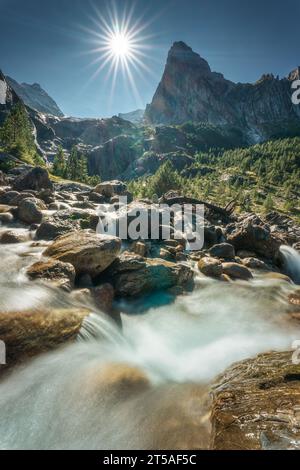 Landschaft Schweizer Alpen des Wetterhorns Gipfel mit Sonnenschein und Wasserfall, der bei sonnigem Tag am Reichenbach, Rosenlaui, Schweiz fließt Stockfoto