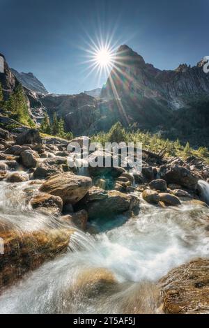 Landschaft Schweizer Alpen des Wetterhorns Gipfel mit Sonnenschein und Wasserfall, der bei sonnigem Tag am Reichenbach, Rosenlaui, Schweiz fließt Stockfoto