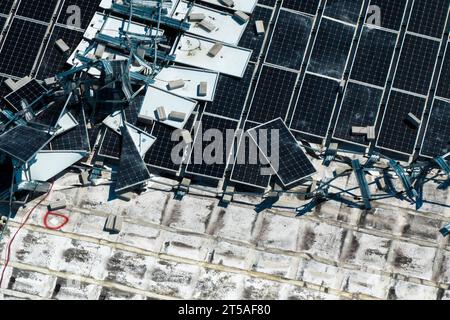 Draufsicht der durch den Hurrikan Ian zerstörten Photovoltaik-Solarpaneele, die auf dem Dach des Industriebaues zur Erzeugung von ökologischem Strom montiert sind Stockfoto