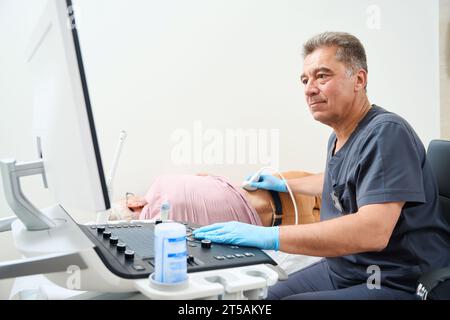 Der Arzt führt eine Ultraschalluntersuchung an einem älteren Mann durch Stockfoto