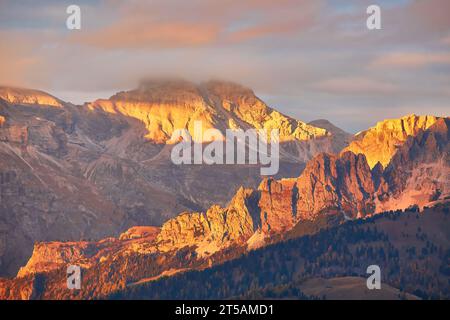 Atemberaubende Luftaufnahme der Dolomitenalpen bei sonnigem Herbsttag mit gelben Lärchen unten und Tal bedeckt von Nebel und hohen Berggipfeln dahinter. Corti Stockfoto