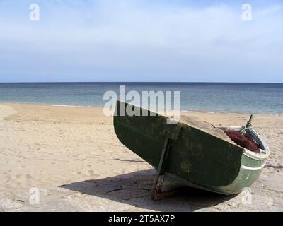 Sesimbra, Portugal. Altes traditionelles Fischerboot namens Aiola, gefüllt mit Fischernetzen am Strand von Sesimbra und im Atlantischen Ozean. Stockfoto
